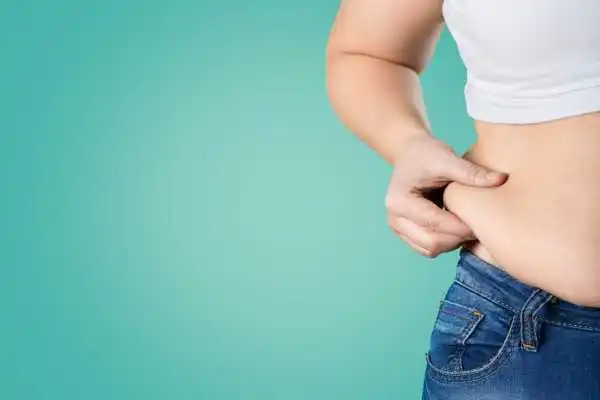 Image of woman pinching her love handles to show weight gain Poole