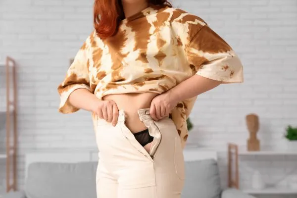 Image of woman trying to do her trousers up after pregnancy weight gain Poole
